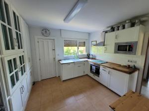 a kitchen with white cabinets and a clock on the wall at Tu escapada soñada entre el mar y la montaña! in La Isla