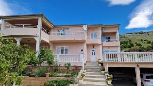 a large pink house with stairs in front of it at Big Apartments in Grebaštica