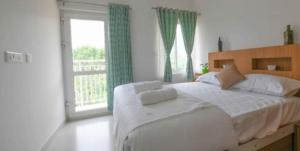 a bedroom with a large bed and a large window at Rains Valley Resort By Teal Luxury Stays in Viripara
