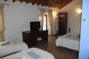 Un dormitorio con dos camas y un televisor. en Habitaciones Andaluzas, en Ronda