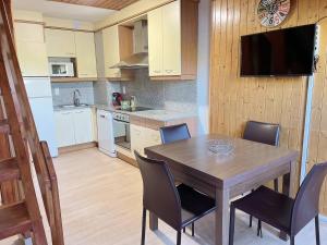 Una cocina con una mesa de madera con sillas y un televisor. en Duplex 2Escales by Confortsky, en Pas de la Casa
