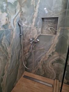 a shower in a bathroom with a marble wall at Pension Delfini in Asprovalta