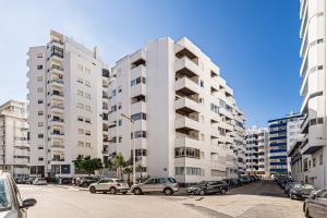 a parking lot with cars parked in front of tall buildings at Casa Verde in Armação de Pêra