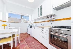 a kitchen with white cabinets and a table and a stove at Casa Verde in Armação de Pêra