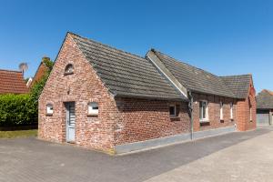 a red brick building with a black roof at Alte Bäckerei Hamswehrum in Krummhörn