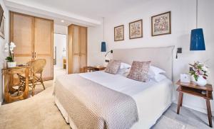 a bedroom with a white bed and a table and chairs at La Ferme D'Augustin in Saint-Tropez