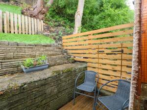 two chairs sitting on a deck next to a wooden fence at Holme Cottage in Hebden Bridge +12 photos
