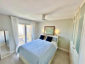 a bedroom with a bed with blue sheets and a window at Ático céntrico con amplias vistas mar y playa in Roses