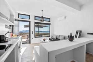 a kitchen and living room with white walls and windows at Amenti Horizon View in Agkidia