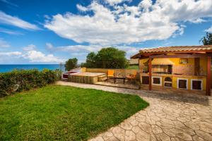 ein Haus mit einer Terrasse und einem Rasenhof in der Unterkunft Galini Beach Villa in Ammoudi