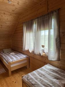 two beds in a log cabin with a window at Resort Dudukovic 2 in Slunj