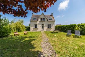 une maison avec des tables de pique-nique et des bancs devant elle dans l'établissement Un Air de Famille - proche de la plage, à Pleubian