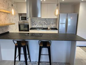 a kitchen with a large counter with two bar stools at GRAN COLLBLANC by CONFORTSKY in Pas de la Casa