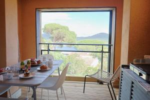 a dining room with a table and a large window at U Mare - T2 cabine avec vue mer, plage & piscine in Pianottoli-Caldarello
