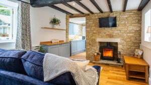 a living room with a blue couch and a fireplace at Little Forge in Bourton on the Water
