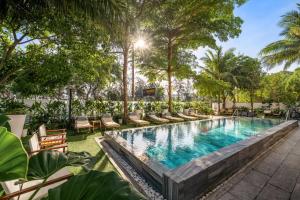 an outdoor swimming pool with chaise lounge chairs and trees at HA Ocean Front Hotel and Apartment in Hoi An +48 photos