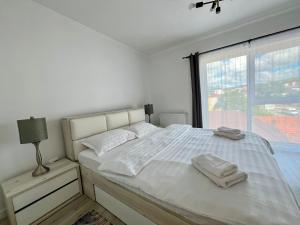 a white bedroom with a bed with two towels on it at Cozy North 35 in Cluj-Napoca