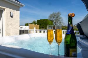 two champagne glasses and a bottle in a hot tub at Fern Cottage - Dog Friendly Cottage with Hot Tub in Begelly