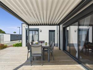 a patio with a table and chairs on a deck at Chalet pour 6, residence avec piscine in Brétignolles-sur-Mer