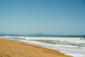 a sandy beach with waves in the ocean at Hôtel Maison Chiberta in Anglet