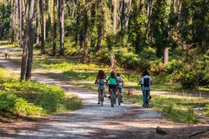 three girls riding bikes down a dirt road at Hôtel Maison Chiberta in Anglet