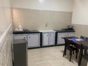 a kitchen with white cabinets and a table with chairs at Appartements Playa NDB City in Nouadhibou