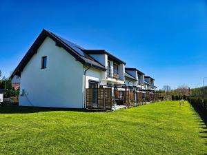 a row of houses on a green lawn at Baltic Harmony Villas - Grzybowo in Grzybowo