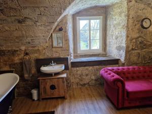 La salle de bains est pourvue d'un canapé rouge et d'un lavabo. dans l'établissement Schlossgut Franken - Schlossapartment Iring, à Redwitz an der Rodach 18 autres photos
