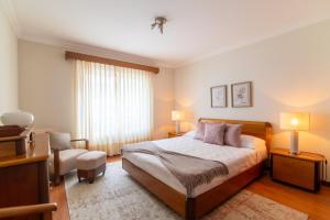 Un dormitorio con una cama y una silla y una ventana. en SUN Apartment, en Rosto de Cão 7 fotos más