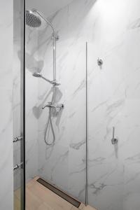 a bathroom with a shower with white marble walls at Elite Apartments Old Town Center Premium in Gdańsk