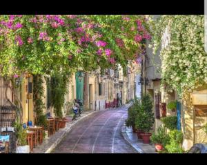 an empty street with pink flowers hanging from buildings at Konstantinos Apartments in Kholargós