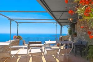 un patio avec tables et chaises et vue sur l'océan dans l'établissement AMORE RENTALS - Villa Vanessa, à Positano