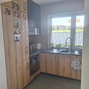 a kitchen with wooden cabinets and a sink and a window at Wiejski Zakątek in Domasławice