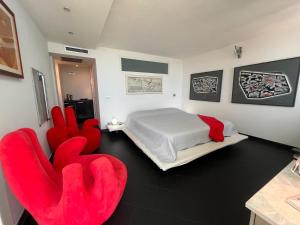 マリーナ・ディ・アンドーラにあるMaison Art sur la Merのベッドルーム1室(ベッド1台、赤い椅子2脚付)