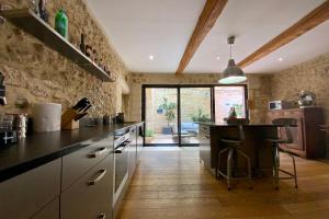 a large kitchen with a counter and a table at La Maison de la Place - Charming house with swimming pool & exposed stone in Mudaison +36 photos