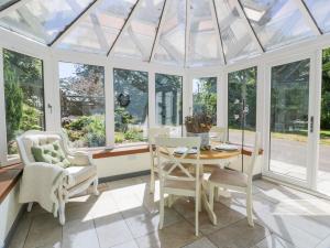 een serre met een tafel, stoelen en ramen bij Nithbank Cottage in Thornhill