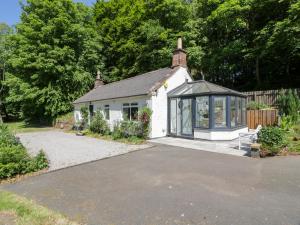 een klein wit huis met veel ramen bij Nithbank Cottage in Thornhill