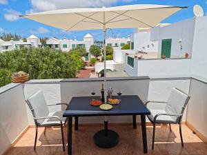 una mesa y sillas en un balcón con sombrilla en Casa Eric, en Playa Blanca
