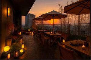 苏州奇遇派空中庭院度假酒店的日落时分带桌子和遮阳伞的屋顶露台