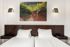 two beds in a room with a painting on the wall at White Waters Hotel in Machico