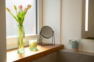 uno specchio e un vaso con fiori sul davanzale di una finestra di STRANDHAUS GRÖMITZ 2 a Grömitz Altre 51 foto