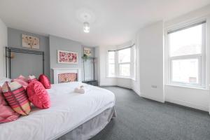 a bedroom with a large white bed with pink pillows at Five bedroom house in Douglas road in Bristol +46 photos