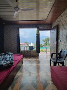 a room with a bed and a chair and a window at Kedar Avnita Resort in Gupta Kāshi