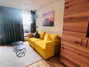 a living room with a yellow couch and a table at Hoisler's Appartements in Ehrwald