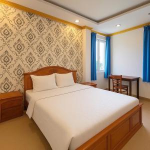 Un dormitorio con una gran cama blanca y una mesa. en K&T Hotel- Aparment SaiGon Center, en Ho Chi Minh