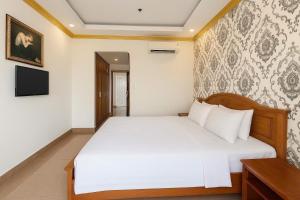 Un dormitorio con una cama blanca y un televisor. en K&T Hotel- Aparment SaiGon Center, en Ho Chi Minh