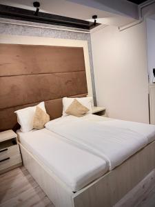a bedroom with a large white bed with a wooden headboard at Studio Central Park in Galaţi