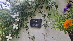 コンウィにあるGlyn Isa Country House luxury self catering accommodationの花が飾られた壁にロッジと書かれた看板