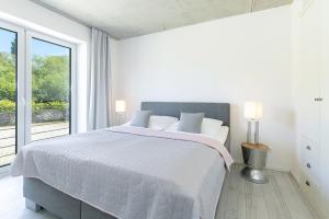 a white bedroom with a bed and a large window at Strandweg 6-7 Dünengras in Möltenort