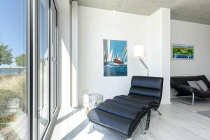 a black leather chair in a room with glass windows at Strandweg 6-7 Dünengras in Möltenort
